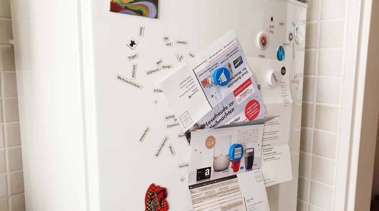 Kühlschrank mit sehr vielen Magneten, an denen Werbesendungen und Gutscheine hängen