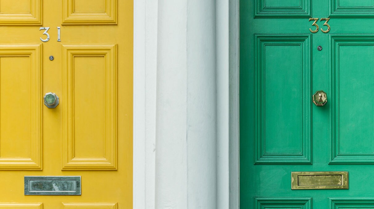 Zwei alte Haustüren mit einem Schlitz für den Briefeinwurf nebeneinander: Die linke in Gelb mit der Nummer 31, die rechte in Grün mit der Nummer 33.